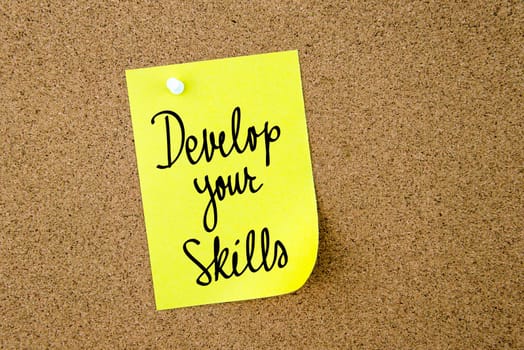 Develop Your Skills written on yellow paper note pinned on cork board with white thumbtacks, copy space available