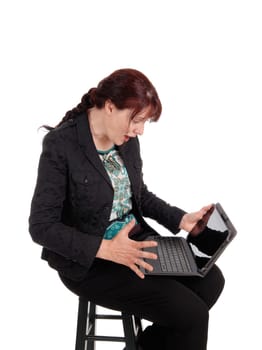 A middle age businesswoman sitting on a chair and wondering what is.on her laptop screen, isolated for white background..