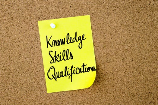 Knowledge Skills Qualifications written on yellow paper note pinned on cork board with white thumbtacks, copy space available