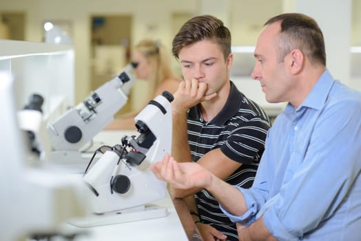 Teacher with student at microscope