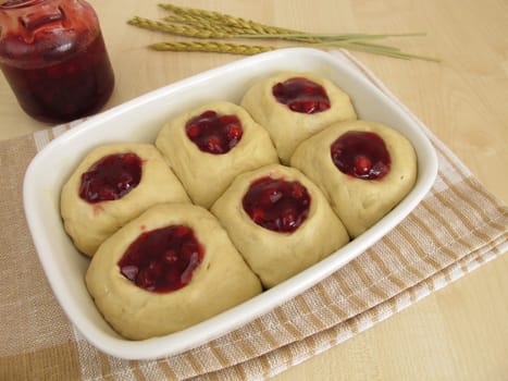 Raw yeast dough with cranberry jam in the baking pan for baking buchteln