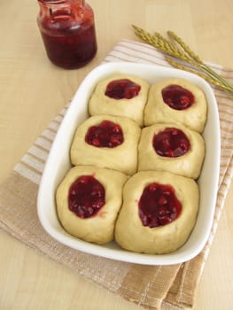 Raw yeast dough with cranberry jam in the baking pan for baking buchteln
