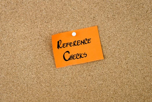 Reference Checks written on orange paper note note pinned on cork board with white thumbtack, copy space available