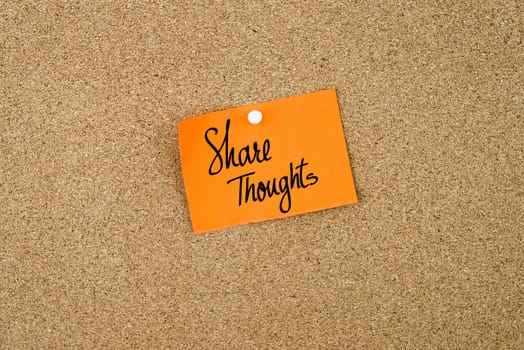 Share Thoughts written on orange paper note note pinned on cork board with white thumbtack, copy space available
