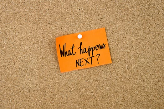 What Happens Next ? written on orange paper note note pinned on cork board with white thumbtack, copy space available