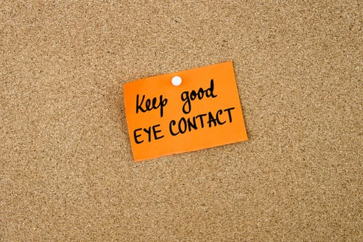 Keep Good Eye Contact written on orange paper note note pinned on cork board with white thumbtack, copy space available