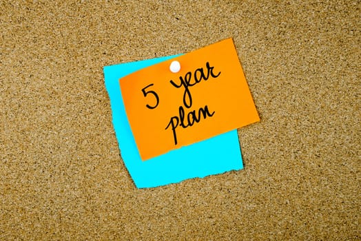 Five Year Plan written on paper notes pinned on cork board with white thumb tack, copy space available