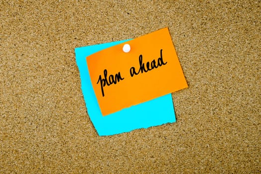 Plan Ahead written on paper notes pinned on cork board with white thumb tack, copy space available