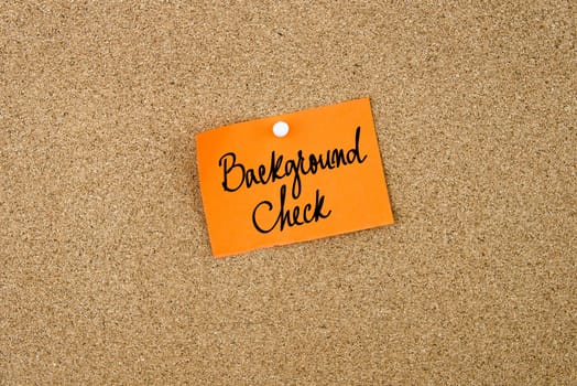Background Check written on orange paper note note pinned on cork board with white thumbtack, copy space available