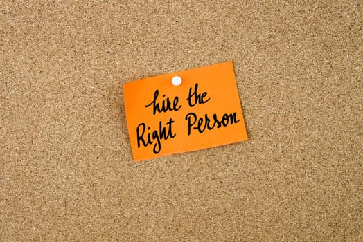 Hire The Right Person written on orange paper note note pinned on cork board with white thumbtack, copy space available