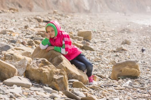 A bored tired girl lay down on a big rock by the sea