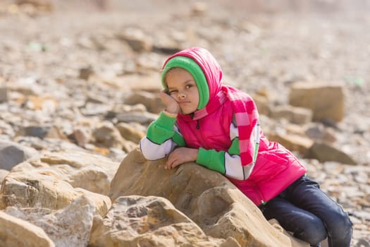 Girl bored at the seaside in the offseason lay down on a big rock