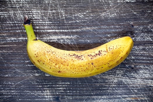 Yellow banana on dark wooden background. Top view.