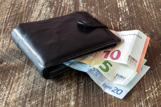 Black leather  wallet with euro banknotes on the wooden table