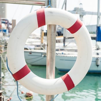 White life buoy hanging from a railing at the port.