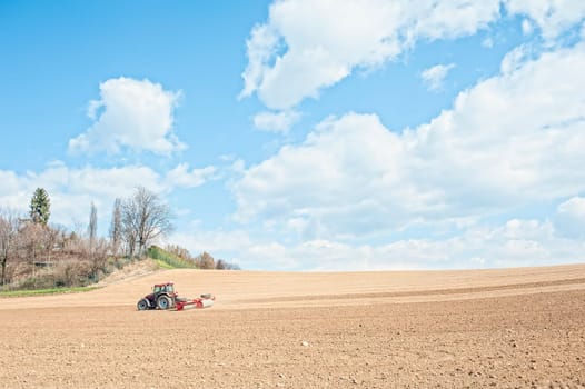Farm work. Tractor compresses the soil after planting with rollers.