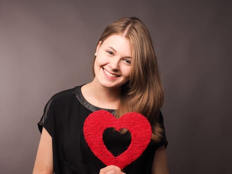 Young happy woman with shape of red heart, health care or love concept image