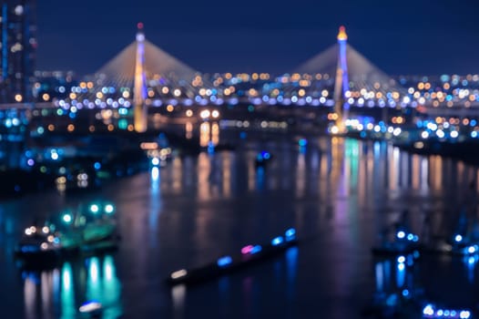 Blurred city skyline bokeh lights illuminated at night with reflection on river