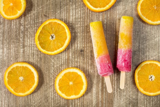 Popsicles with sliced orange fruit on wooden background. Top-view.