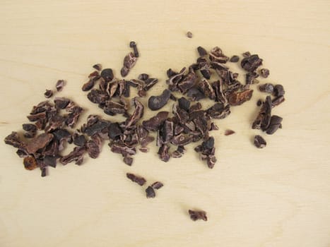 Cocoa nibs from raw cocoa beans on a wooden board