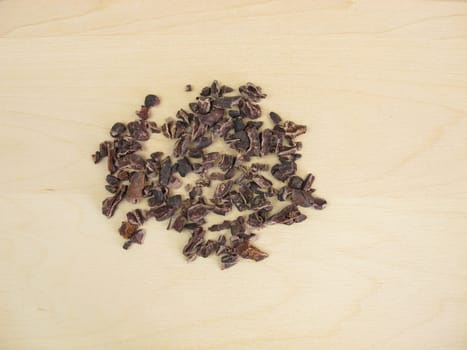 Cocoa nibs from raw cocoa beans on a wooden board