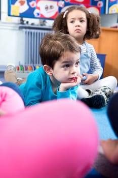 Little boy lying on the floor at nursery during story time.