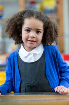 Portrait of a school girl. She is wearing a blue cardigan and smiling at the camera.