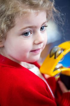 Close up of a little girl playing with a tambourine at school.