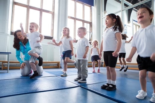 Nursery teacher helping one of her students during a physical education lesson.