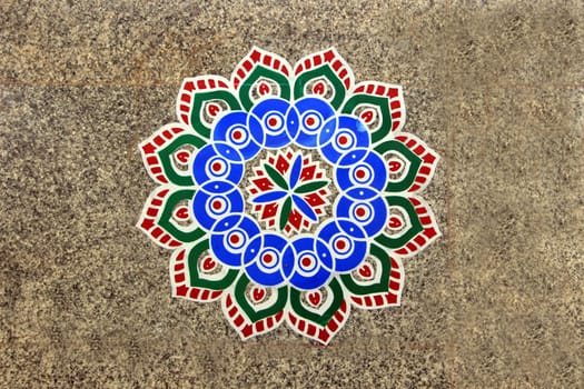 Printed, colorful, geometrical pattern of rangoli stuck on mosaic tiled floor
