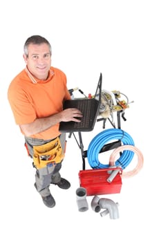 Workman posing with his laptop, tools and building materials