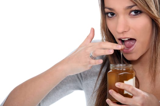 Brunette dipping finger in honey jar