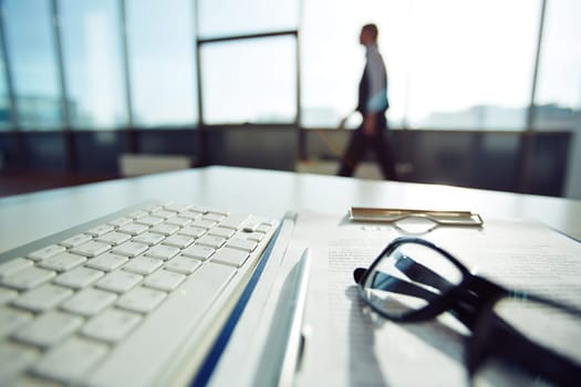 Business objects on workplace in office and employee walking on background
