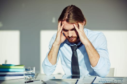 Tense businessman touching his head while looking at display of touchpad