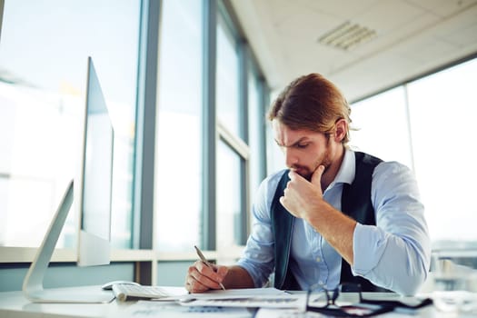 Pensive entrepreneur writing plan of work in office