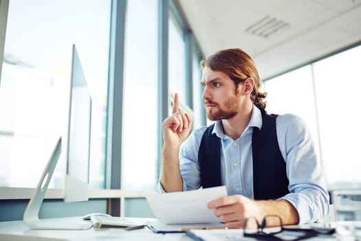Young businessman looking at computer monitor with misunderstanding