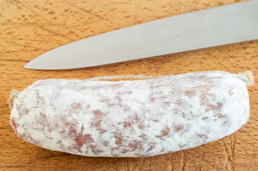 still life of salami whit knifeon a cutting board in studio