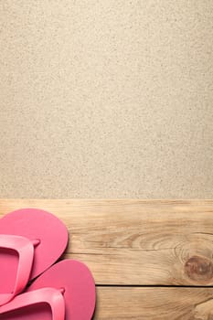 summer background with pink flip flops on sandy beach