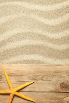 summer concept with yellow starfish on planks and sandy beach