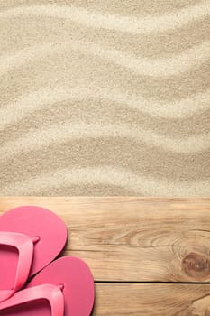 summer concept with pink flip flops on sandy beach