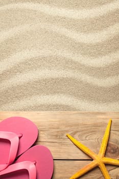 summer concept with pink flip flops and yellow starfish on sandy beach