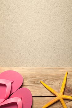 summer background with pink flip flops and yellow starfish on sandy beach