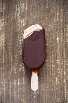 Bitten chocolate covered vanilla ice cream bar on a wooden stick