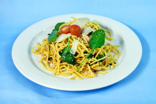 Modern food on a white plate and blue background - spaghetti with salmon and spinach