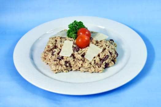Modern food on a white plate and blue background - Italian creamy risotto with mushrooms and cream
