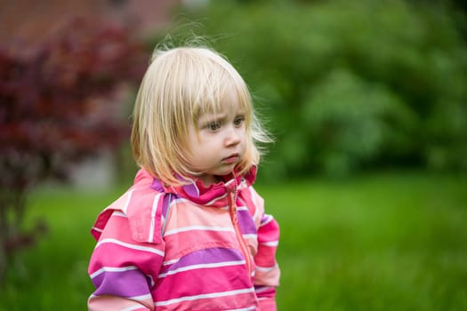 Sad or bewildered girl standing alone in the garden