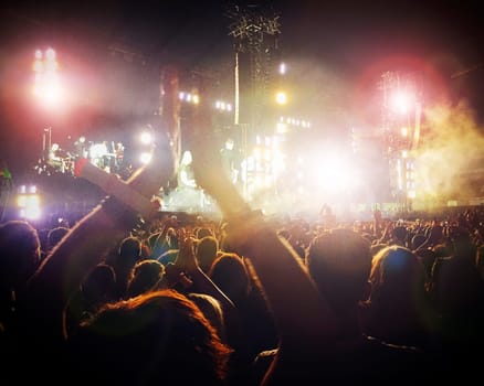 Large crowd at a concert. It is dark and there are colourful lights.