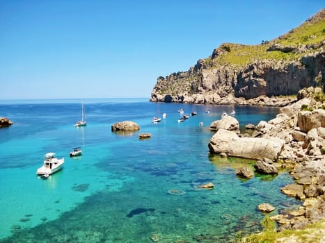 Boats and yachts at bay Cala Figuera, Majorca, Spain - crystal clear turquoise ocean water with rocks aside