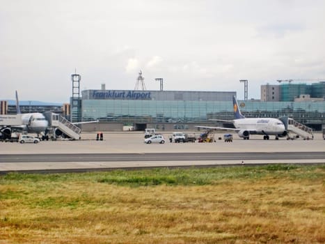 Frankfurt am Main, Germany - July 9, 2008: Airport Frankfurt / Main - Terminal labeled with Frankfurt Airport with Lufthansa airplane in parking position - runway and meadow in front.