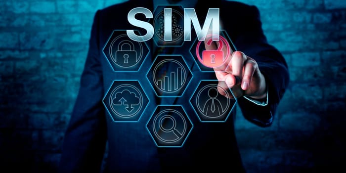 Male cyber security manager is pressing the industry acronym SIM on an interactive touch screen display. Business metaphor and information technology concept for Security information Management.
